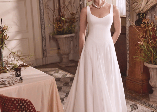Bride wearing a simple A-line wedding dress with a scoop neckline in an elegant indoor setting