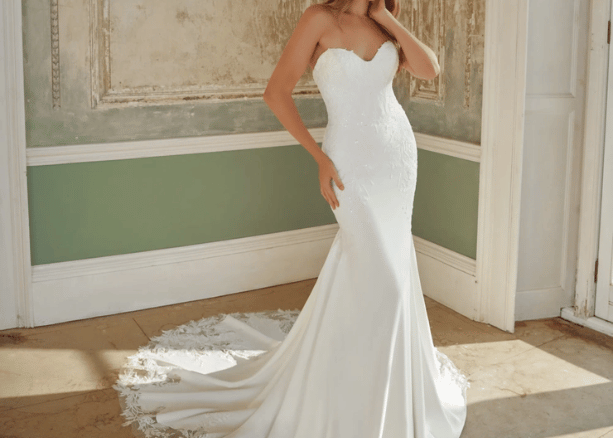 Bride wearing a sweetheart neckline mermaid wedding dress with a fitted silhouette and long lace train indoors.