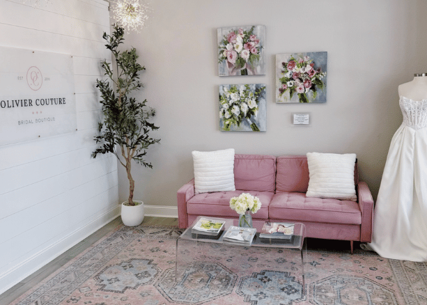 Bridal boutique interior with a pink sofa, floral wall art, and a wedding dress on display