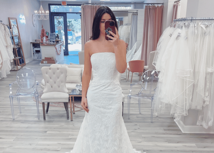 Bride trying on a strapless lace mermaid wedding dress in a bridal boutique fitting room