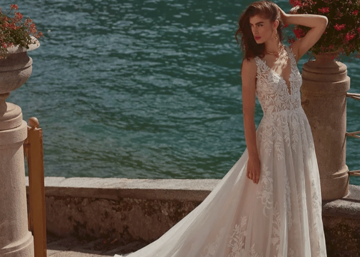 Lace A-line wedding dress with deep V neckline and flowing train by the sea