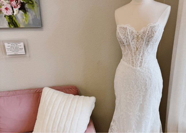 Wedding dress hanging in front of large windows overlooking a garden