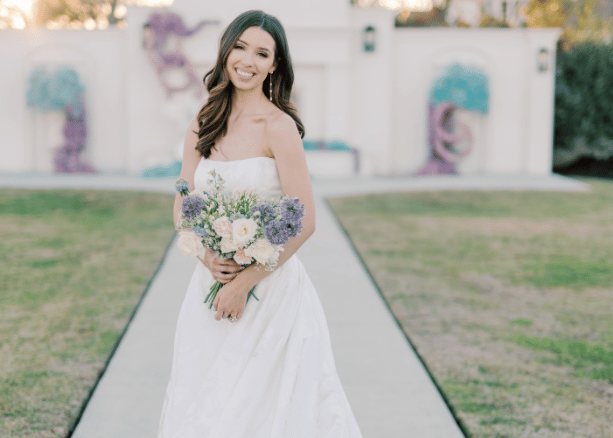 Bride in a classic strapless wedding dress holding a bouquet outdoors