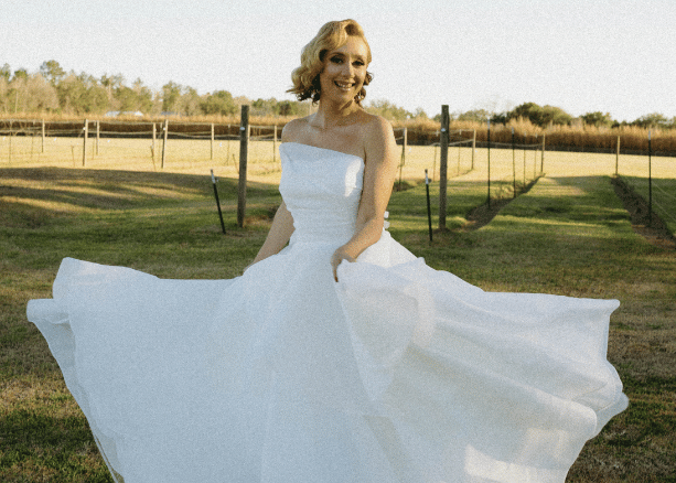 Bride wearing a strapless ball gown wedding dress in a countryside setting