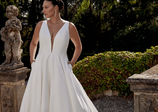 Bride in an elegant V-neck wedding dress standing in a formal garden