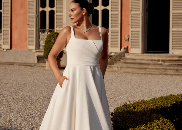 Bride in a simple A-line wedding dress with spaghetti straps at an outdoor venue