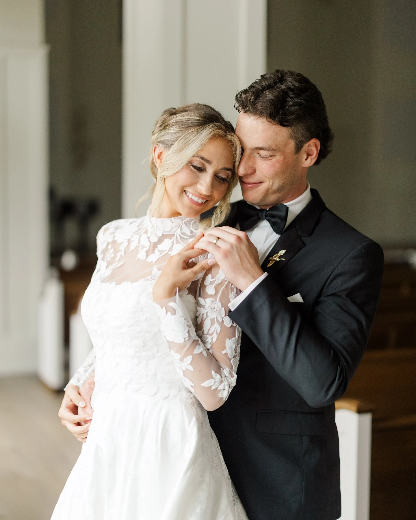 Bride and groom embracing, highlighting the bride's wedding gown with delicate floral lace sleeves